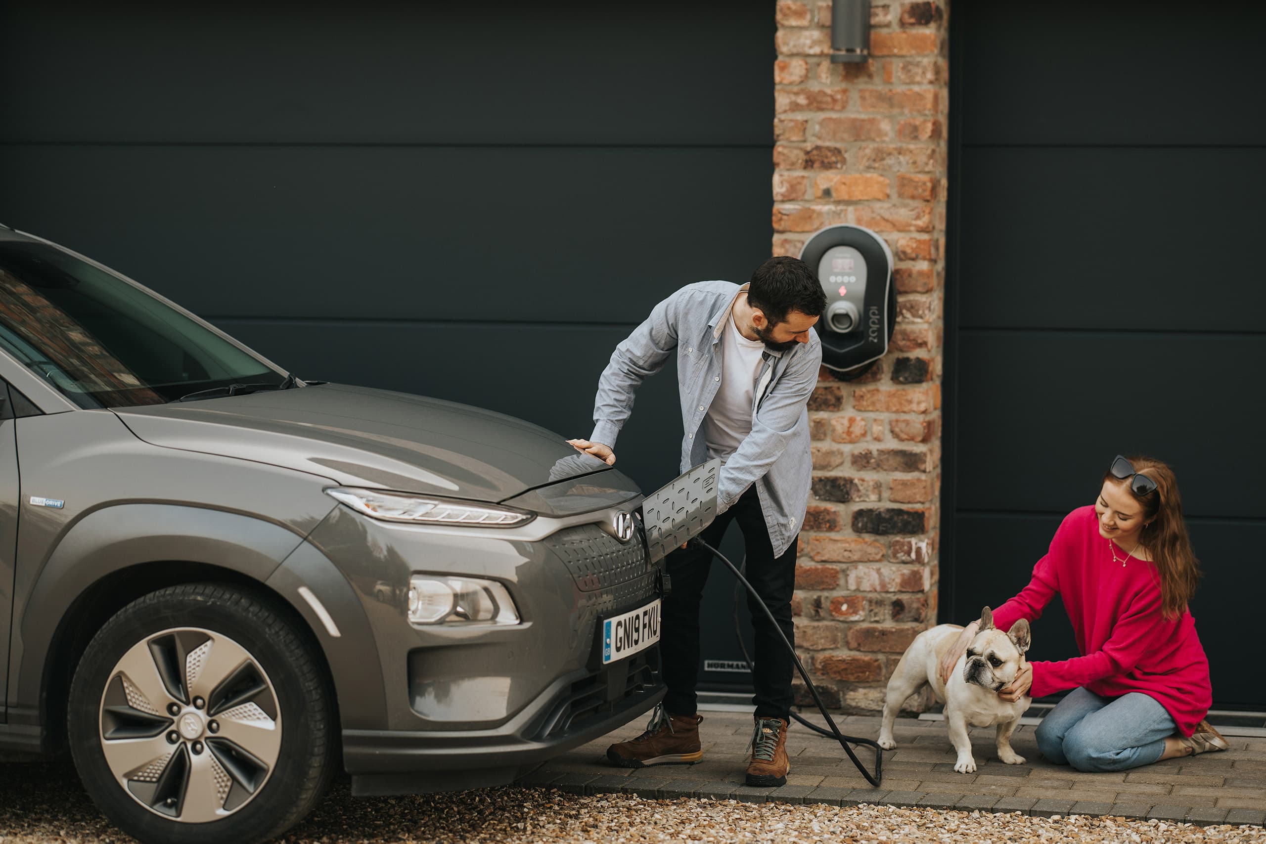 Wall mounted electric car charger with couple and dog